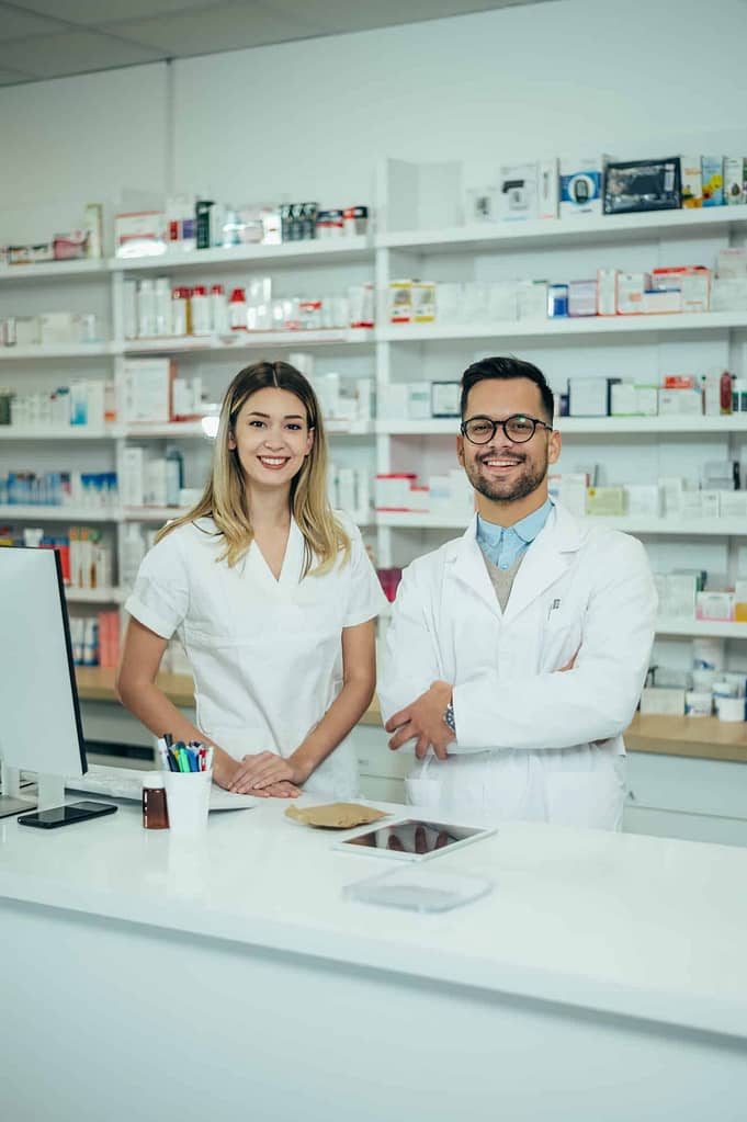 jovens felizes, homens e mulheres, colegas farmacêuticos que trabalham em uma farmácia